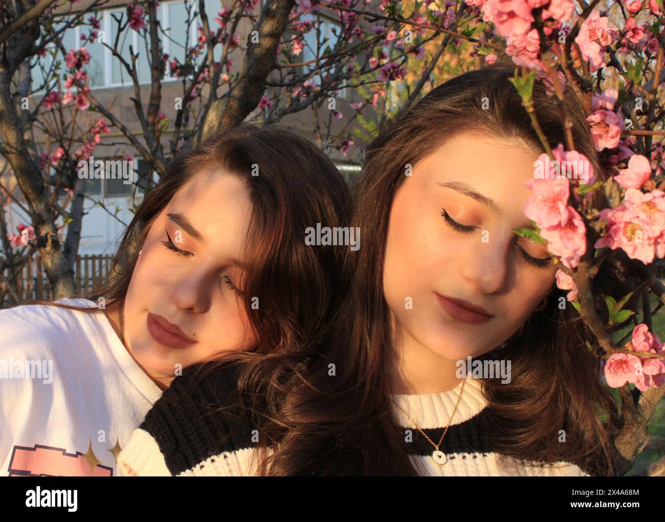 Spring sunny image of 2 girls posing with blossom tree Stock Photo