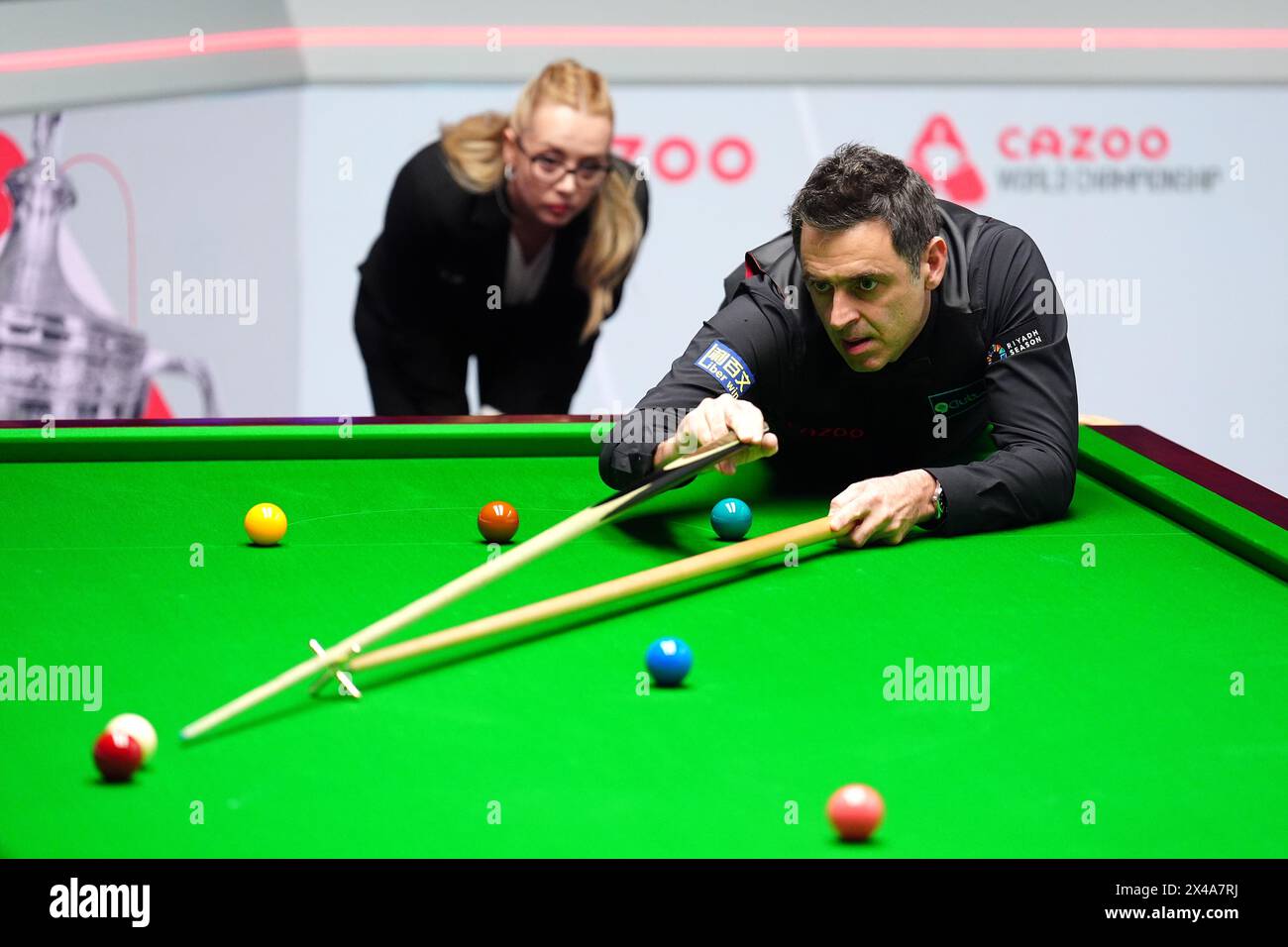 Ronnie O'Sullivan (right) in action against Stuart Bingham (not pictured) as referee Desislava Bozhilova looks on in the quarter-finals match on day twelve of the 2024 Cazoo World Snooker Championship at the Crucible Theatre, Sheffield. Picture date: Wednesday May 1, 2024. Stock Photo