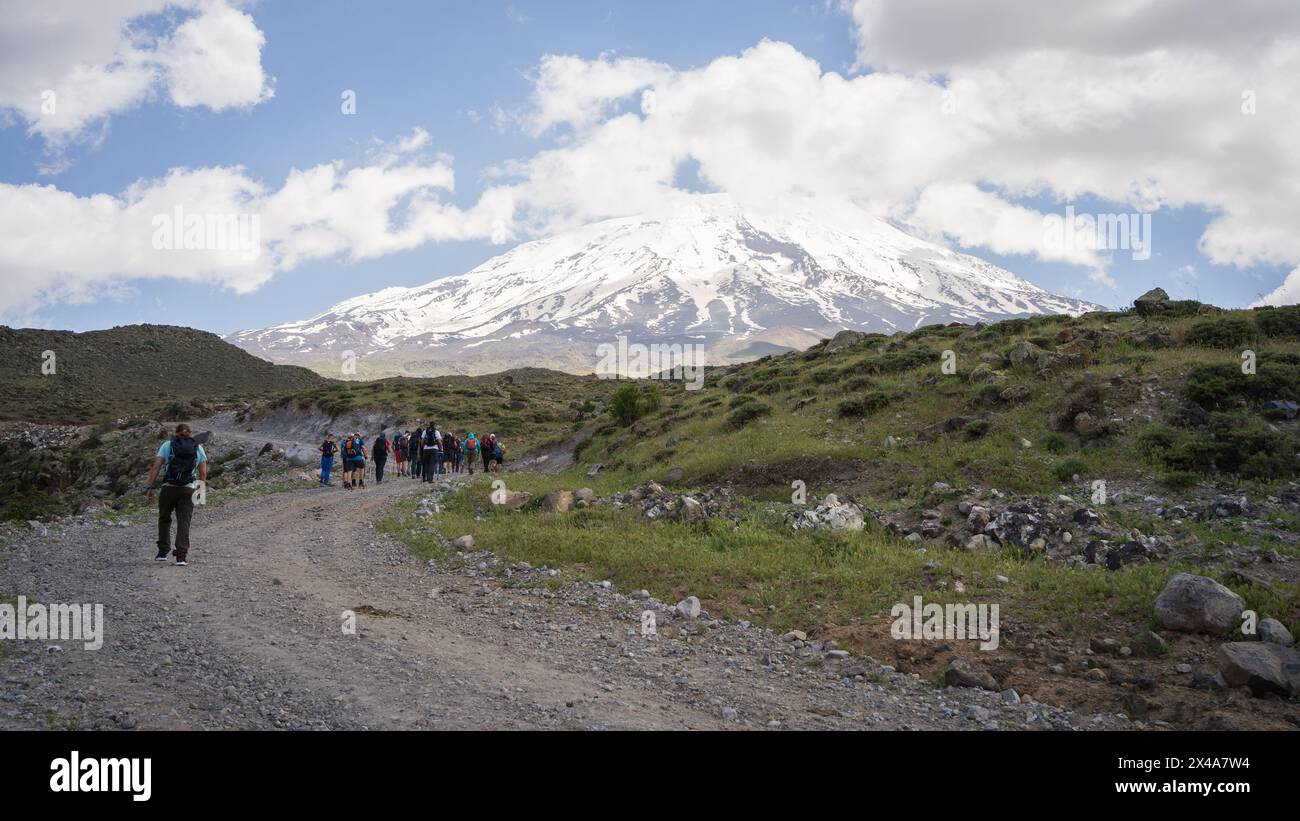 Hikers walking to the basecamp with huge snowy mountain summit in ...