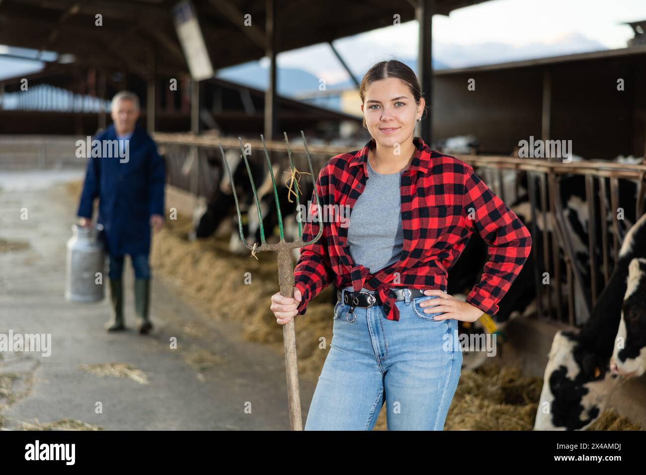 Portrait of positive woman farmer with pitchfork in cowhouse Stock ...