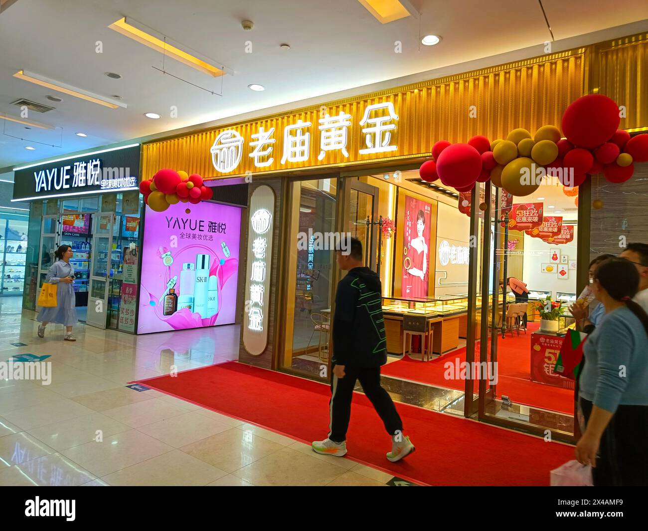 SUQIAN, CHINA - MAY 1, 2024 - Customers pass a gold jewelry store in Suqian, Jiangsu province, China, May 1, 2024. Stock Photo