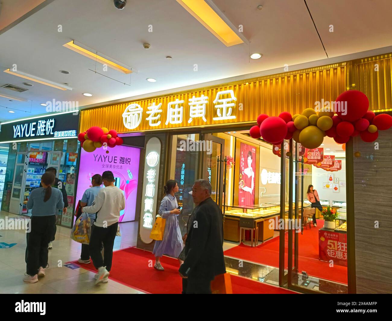 SUQIAN, CHINA - MAY 1, 2024 - Customers pass a gold jewelry store in Suqian, Jiangsu province, China, May 1, 2024. Stock Photo