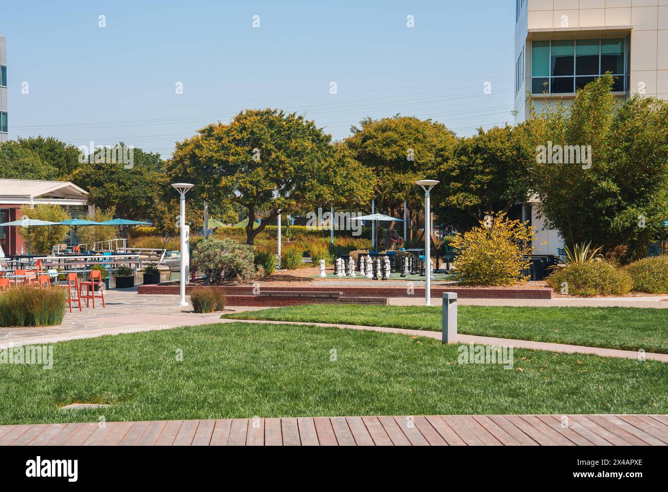 Modern urban park with chess set, tables, and lush landscaping in corporate campus setting. Stock Photo