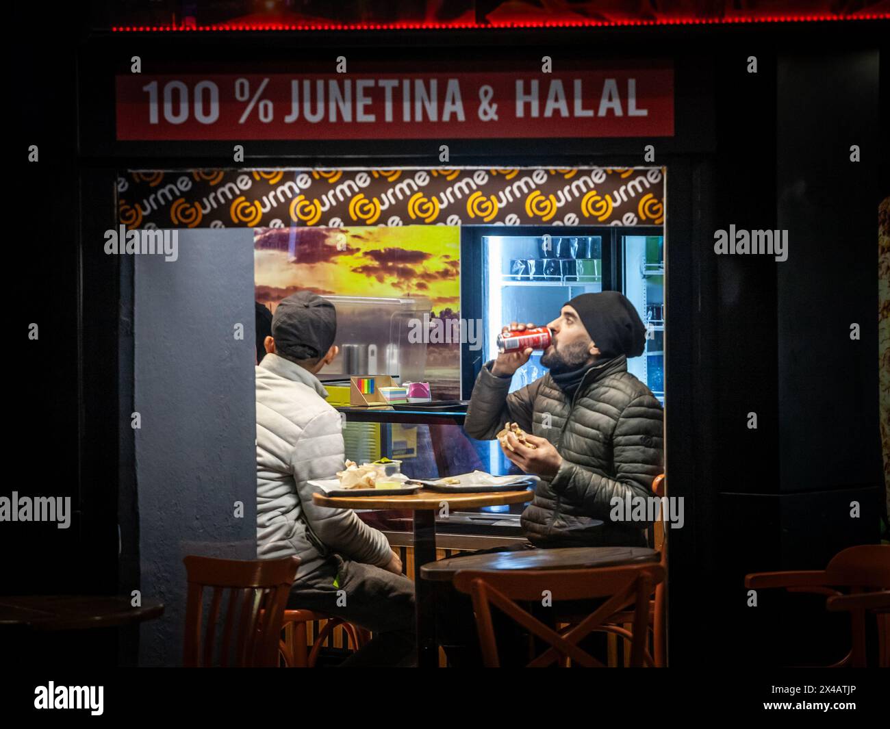 Picture of two men, friends, eating at night in a kebab fastfood restaurant in belgrade, serbia. Stock Photo