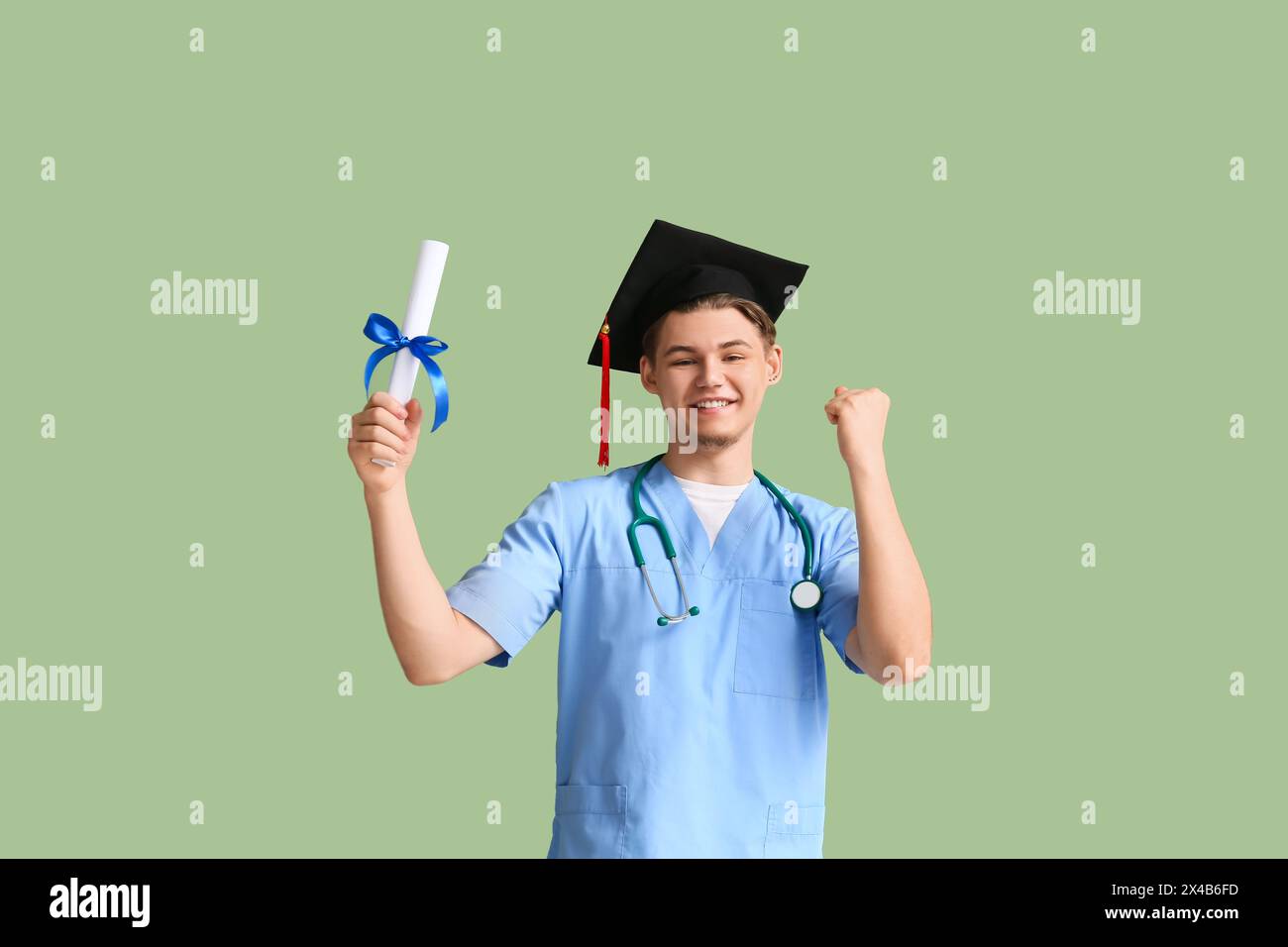 Happy male medical graduate with diploma and stethoscope on green ...