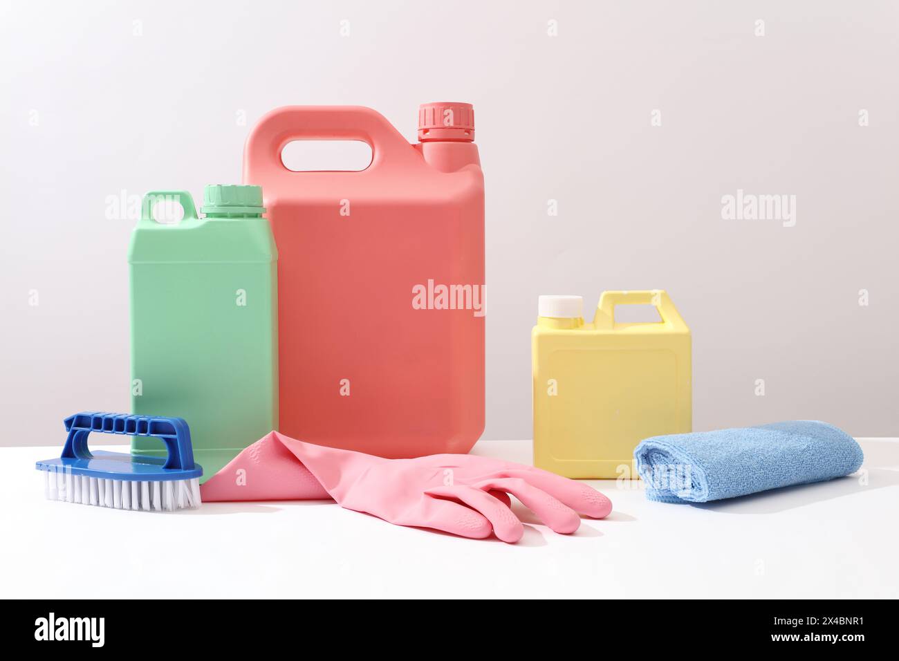 Advertising scene for housework and professional cleaning service supplies. Plastic canisters mockup for detergent product decorated with rubber glove Stock Photo