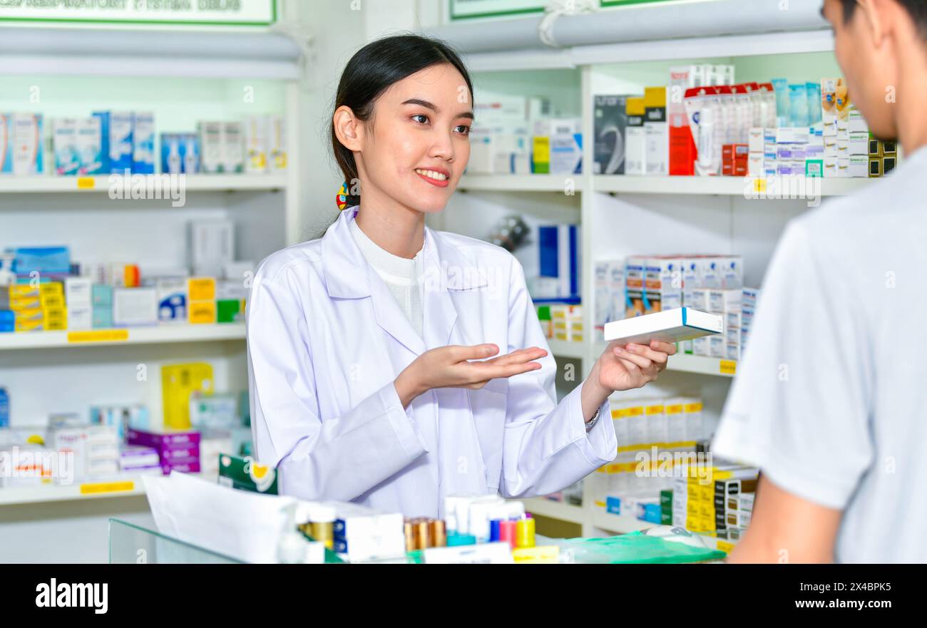Female pharmacist holding medicine box giving advice to customer in pharmacy store Stock Photo
