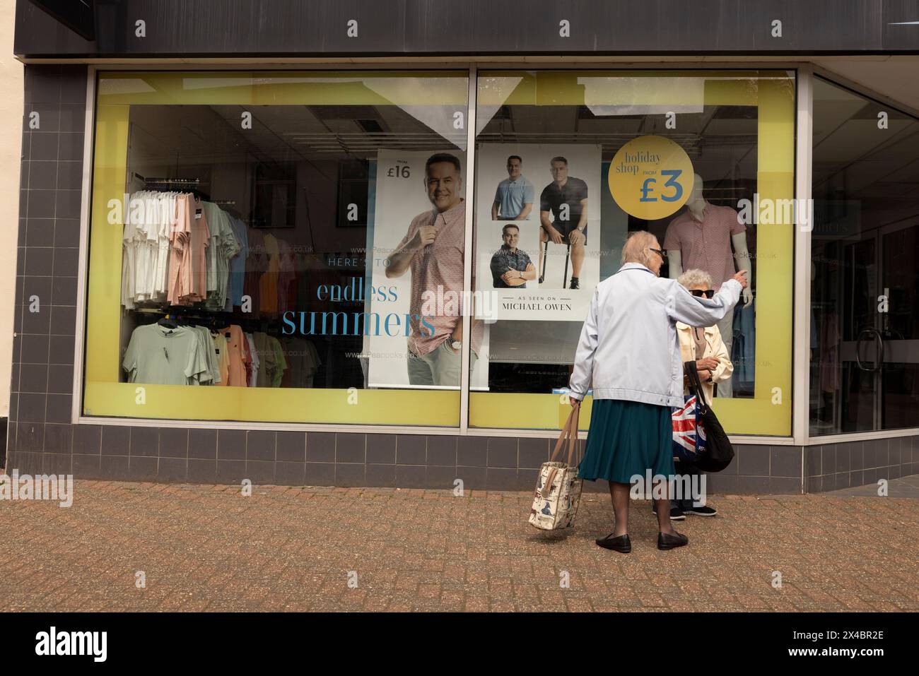 Two elderly ladies at the window display of PEACOCKS clothing chainstore in Leighton Buzzard, Bedfordshire, England, United Kingdom Stock Photo