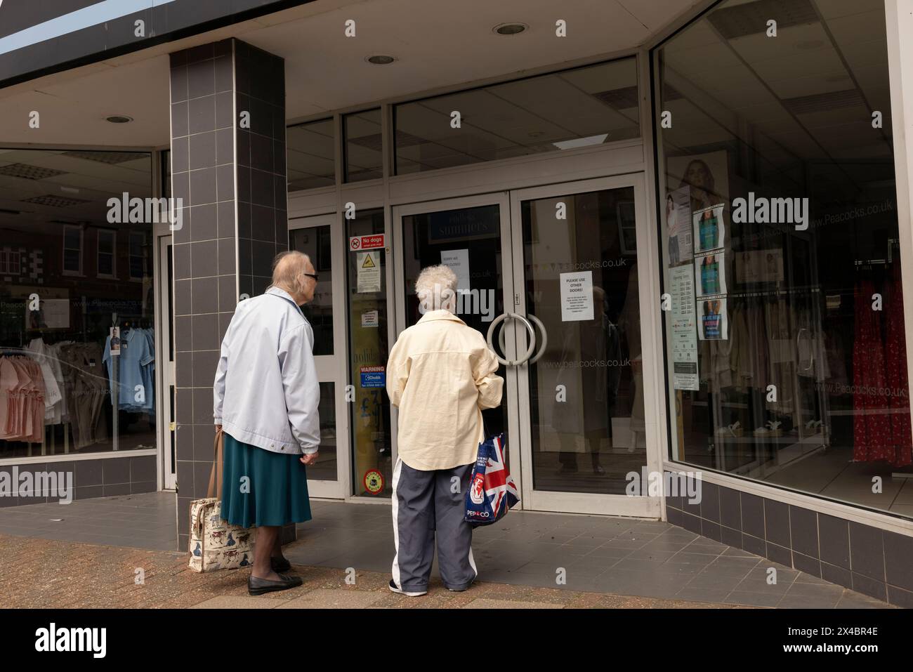 Two elderly ladies at the window display of PEACOCKS clothing chainstore in Leighton Buzzard, Bedfordshire, England, United Kingdom Stock Photo