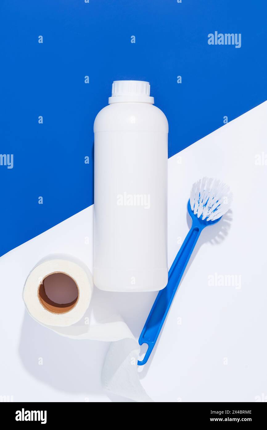 On a white and blue background, an unlabeled white bottle container detergent decorated with brush and paper glove. Space for design packaging. Househ Stock Photo