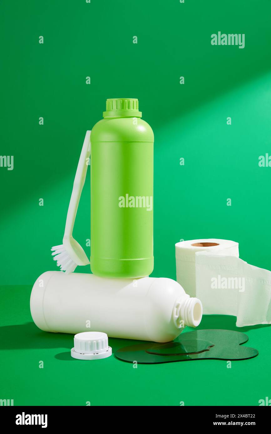 A set of different detergents bottles, brush and paper roll decorated on a green background. Front view, mockup for design packaging. The concept of c Stock Photo