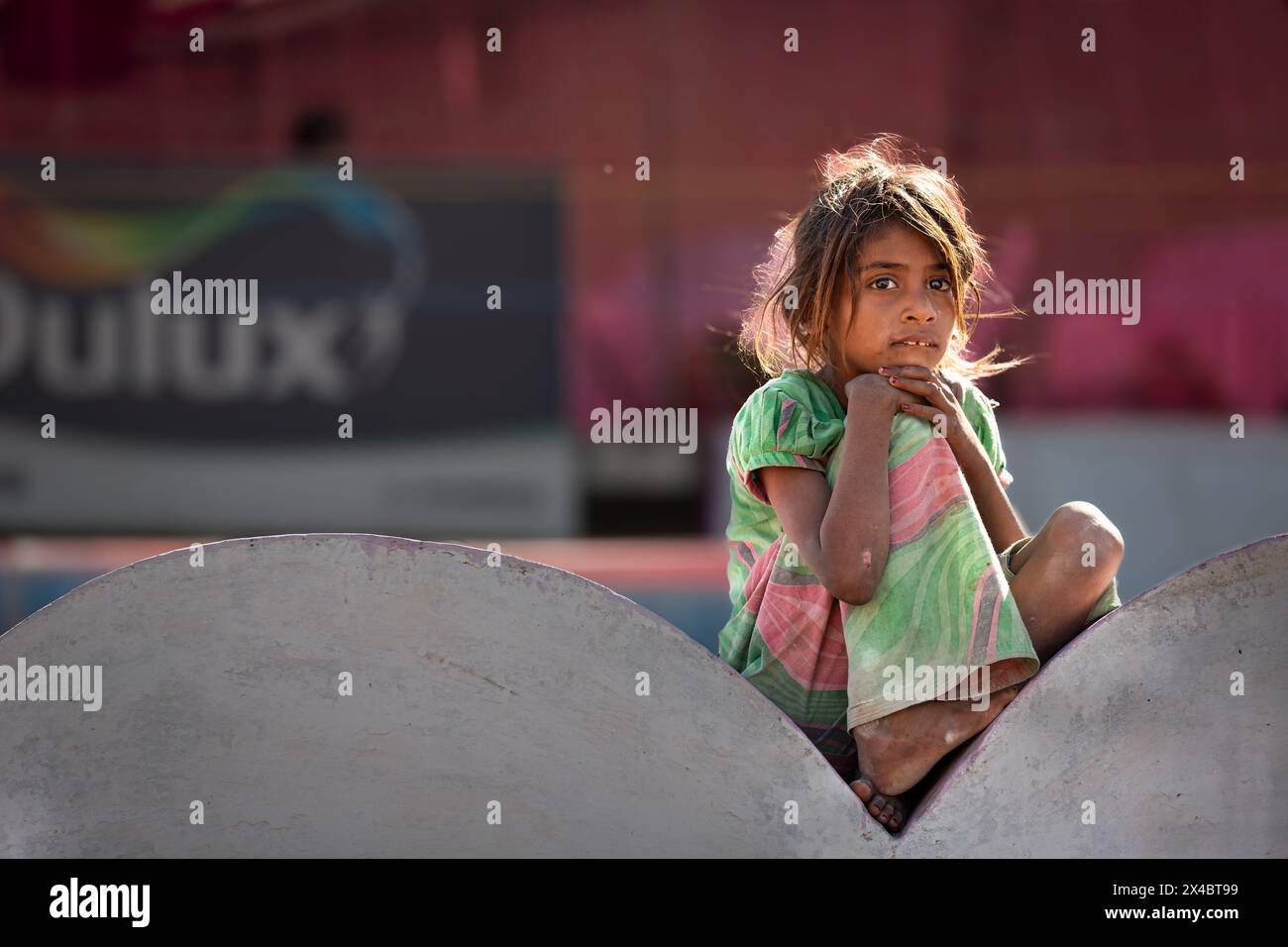 Poor girl sitting on a wall, Pushkar, Rajasthan, India Stock Photo