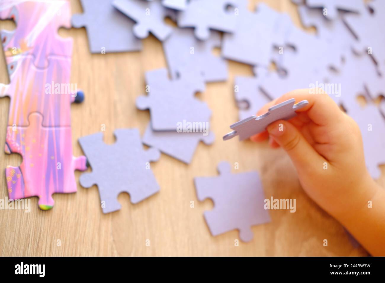 little child assembling puzzles, sorting cardboard pieces by shape