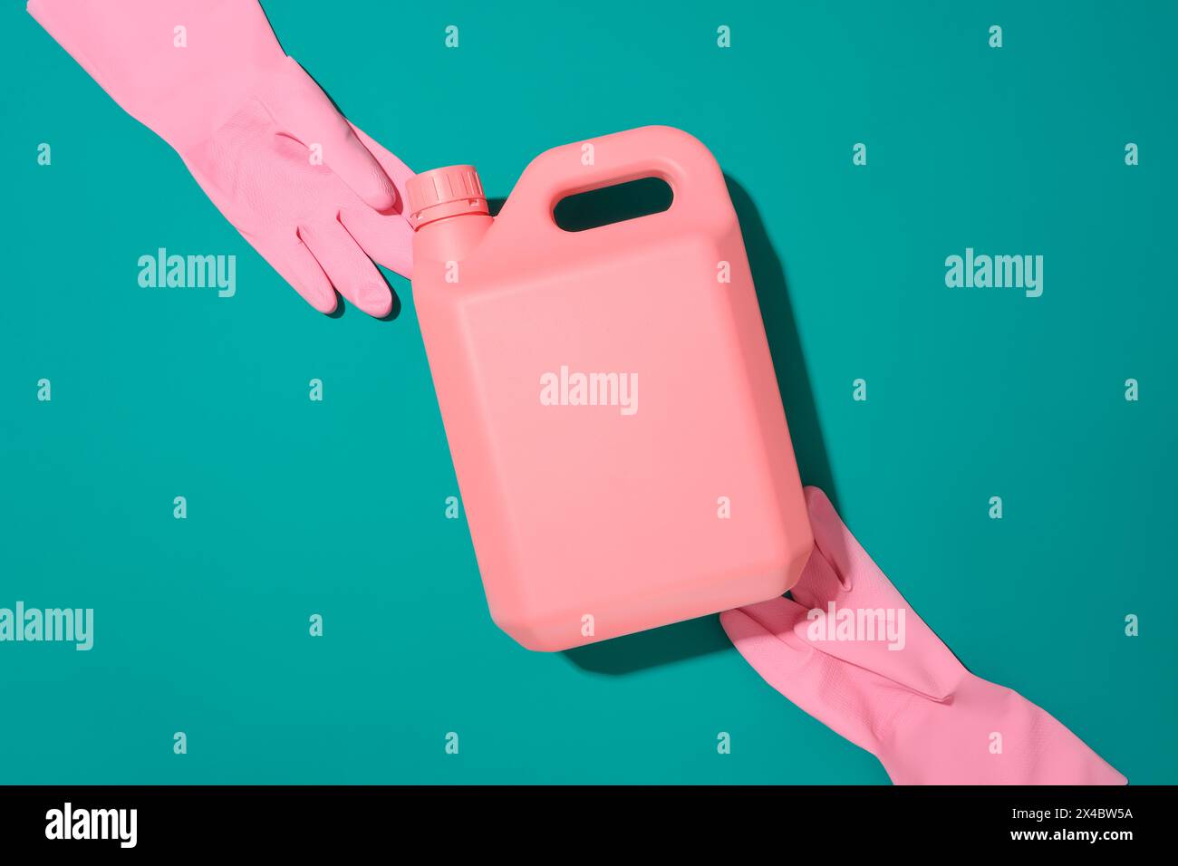 An unlabeled bottle of detergent and a pair of rubber gloves on a turquoise background. Mockup of cleaning products for advertising. Top view. Stock Photo