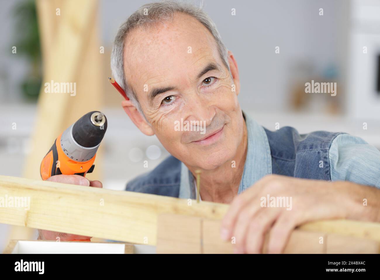 senior carpenter using a cordless screwdriver Stock Photo