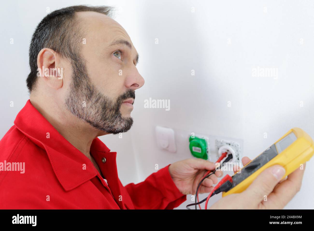 electrician checking socket voltage using multimeter Stock Photo