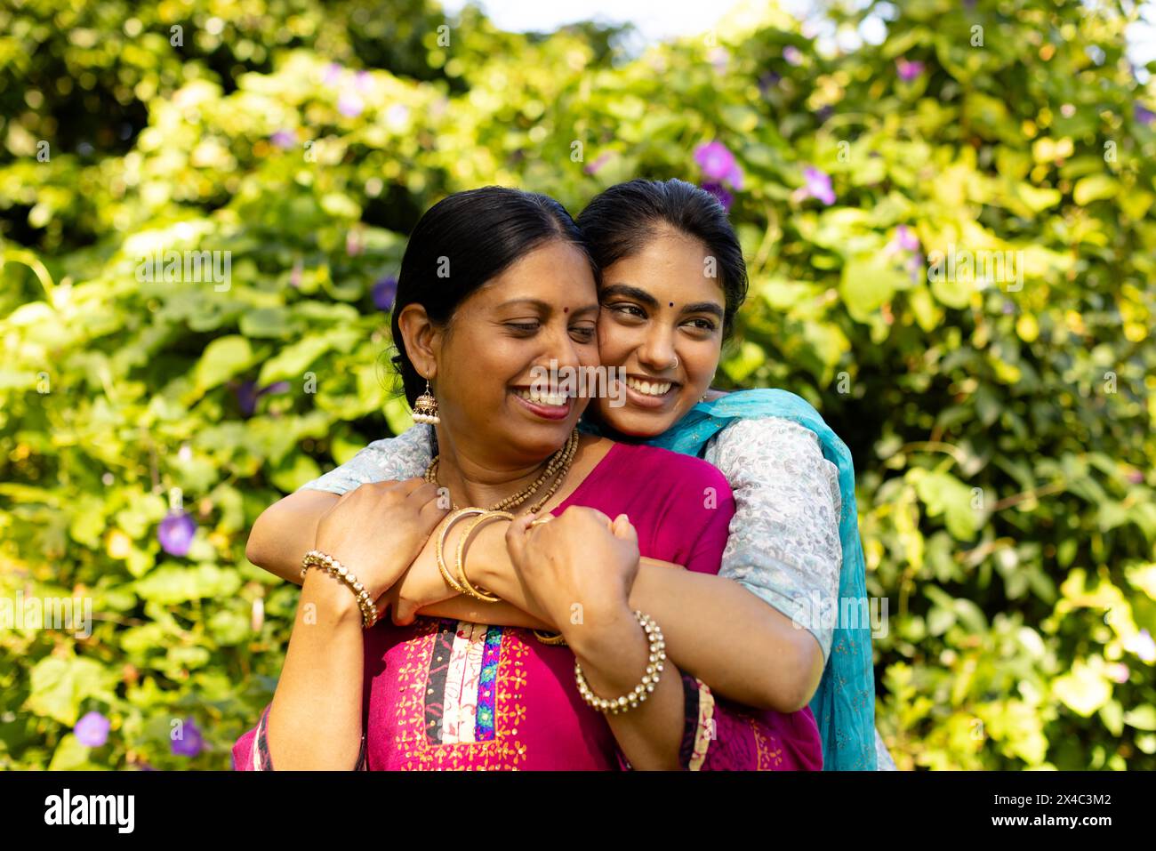 Indian mother and daughter in traditional attire embracing outside. Both with black hair smiling enjoying warm moment together unaltered Stock Photo Alamy