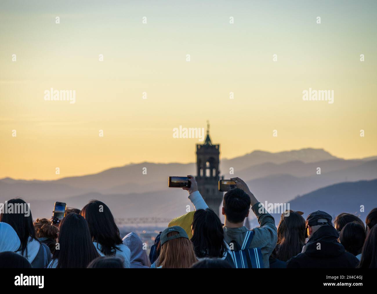 A crowd of tourists holding phones over their heads to take photos of the Florence skyline at Piazzale Michelangelo. An example of overtourism. Stock Photo