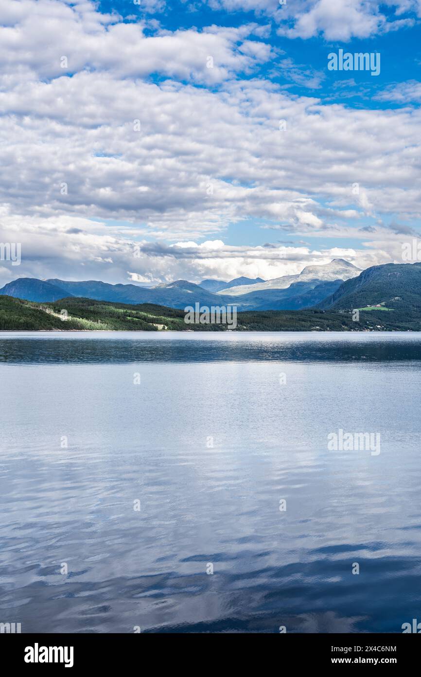 Overlooking calm waters of the Ålvundfjord. View on the fjord coastline with a village against the backdrop of the Trollheimen mountains in Norway Stock Photo
