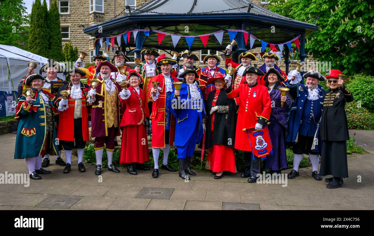 Town criers standing in large group, smile (bellmen & bellwomen in colourful braided uniforms coats) - Ilkley bandstand, West Yorkshire, England UK. Stock Photo