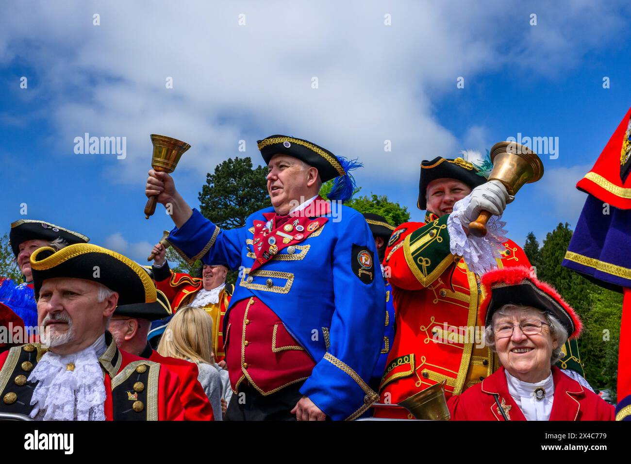 Town criers (bellmen & bellwomen in colourful braided crier's livery & uniforms) standing in group, smile & pose - Ilkley, West Yorkshire, England UK. Stock Photo