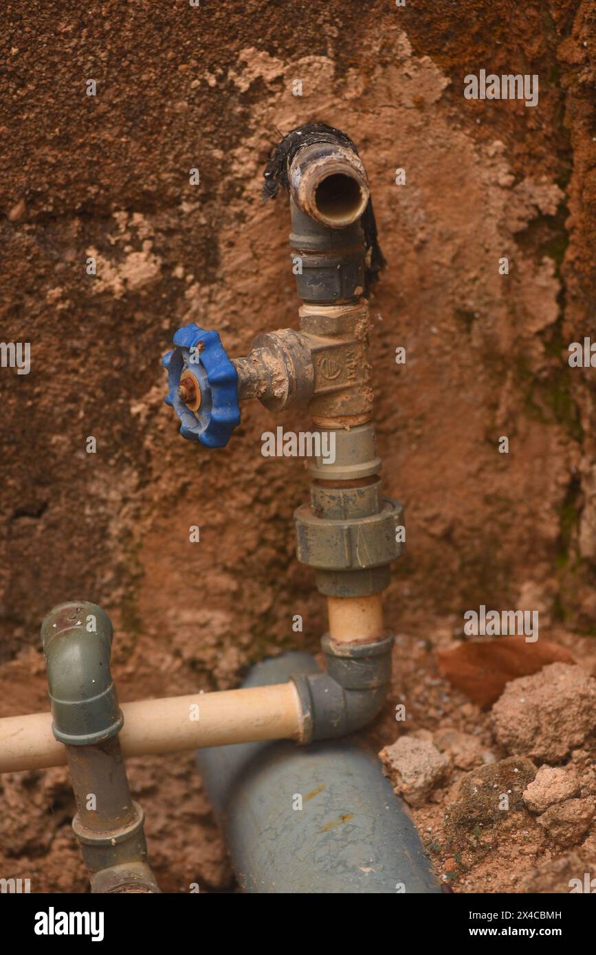 Plumbing pipes passing through a rough concrete wall Stock Photo