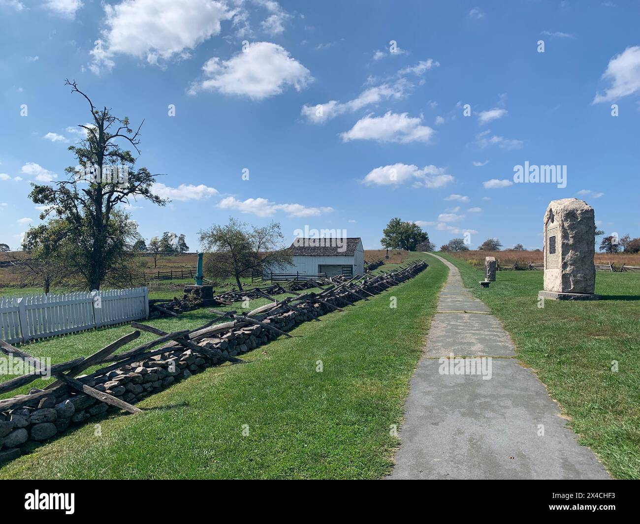 Pathway on the battlefield in Gettysburg National Military Park on sunny day in early fall, clouds. Monuments, markers and fences. The Battle of Getty Stock Photo