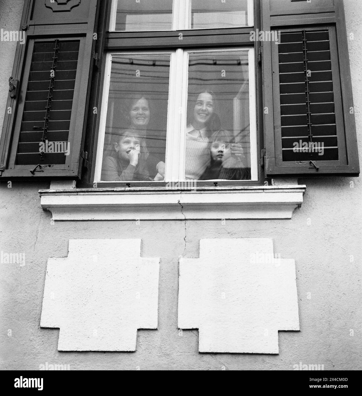 Socialist Republic of Romania in the 1970s. Women and girls in a family seen behind the glass window of their house, looking out. Stock Photo