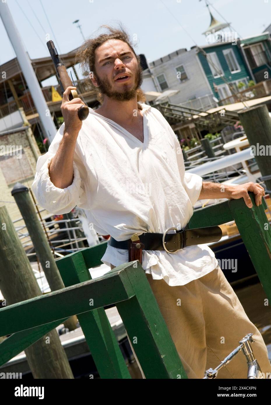 A pirate in full costume shoots a pistol from the deck of the Jolly Rover tall ship, docked on the riverfront in Georgetown, South Carolina, USA. Stock Photo