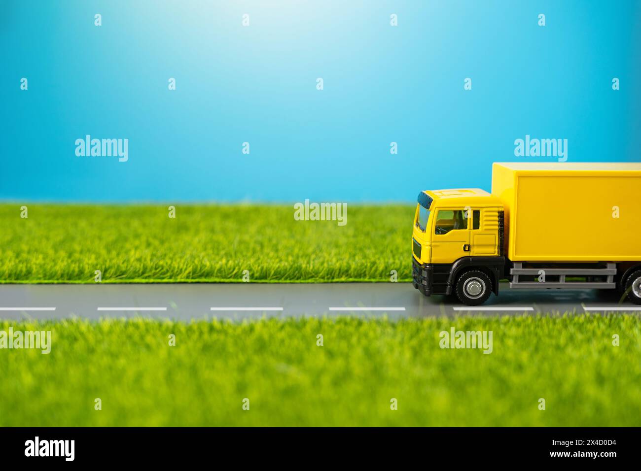 A truck drives along a country road through green meadows. Delivery of online orders and purchases. Supply of goods. Logistics and industry. Stock Photo