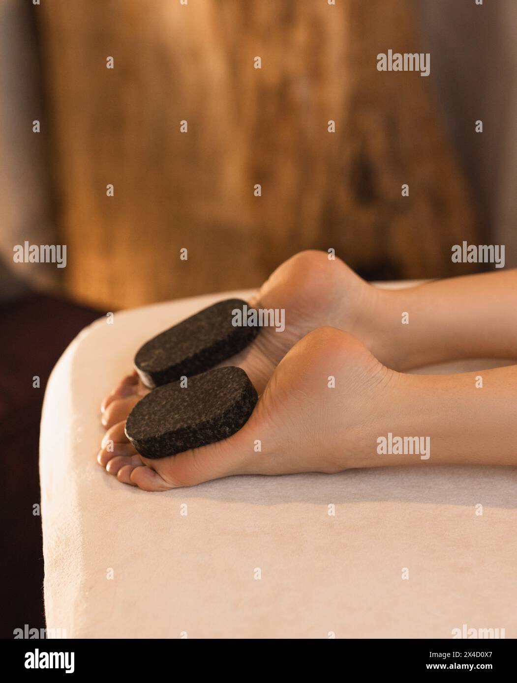 Beautiful legs of woman during massage with hot basalt stones in oriental spa, close-up Stock Photo