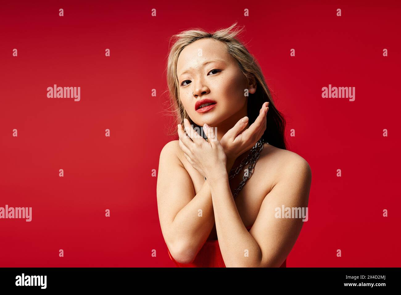 Asian woman in colorful attire gracefully touches her face with hands. Stock Photo