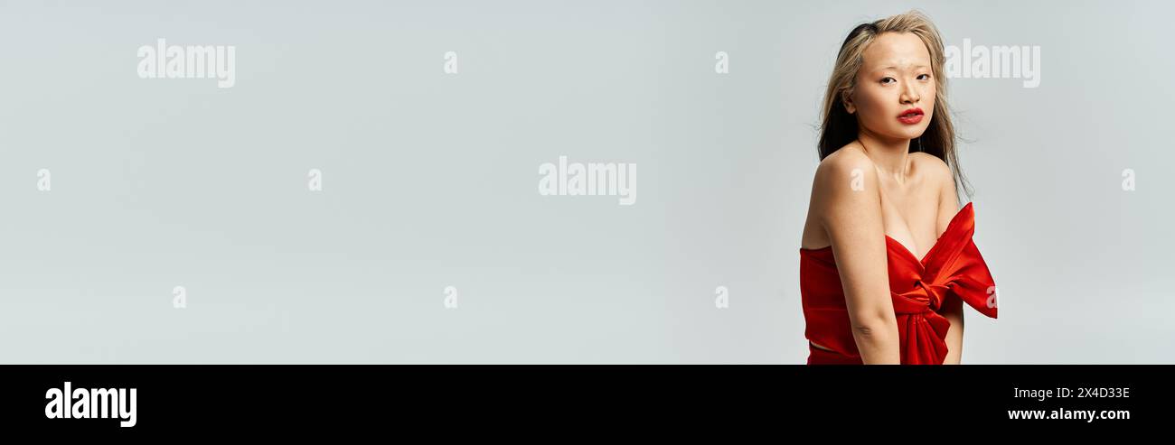 An attractive Asian woman in a vibrant red dress poses gracefully for a ...