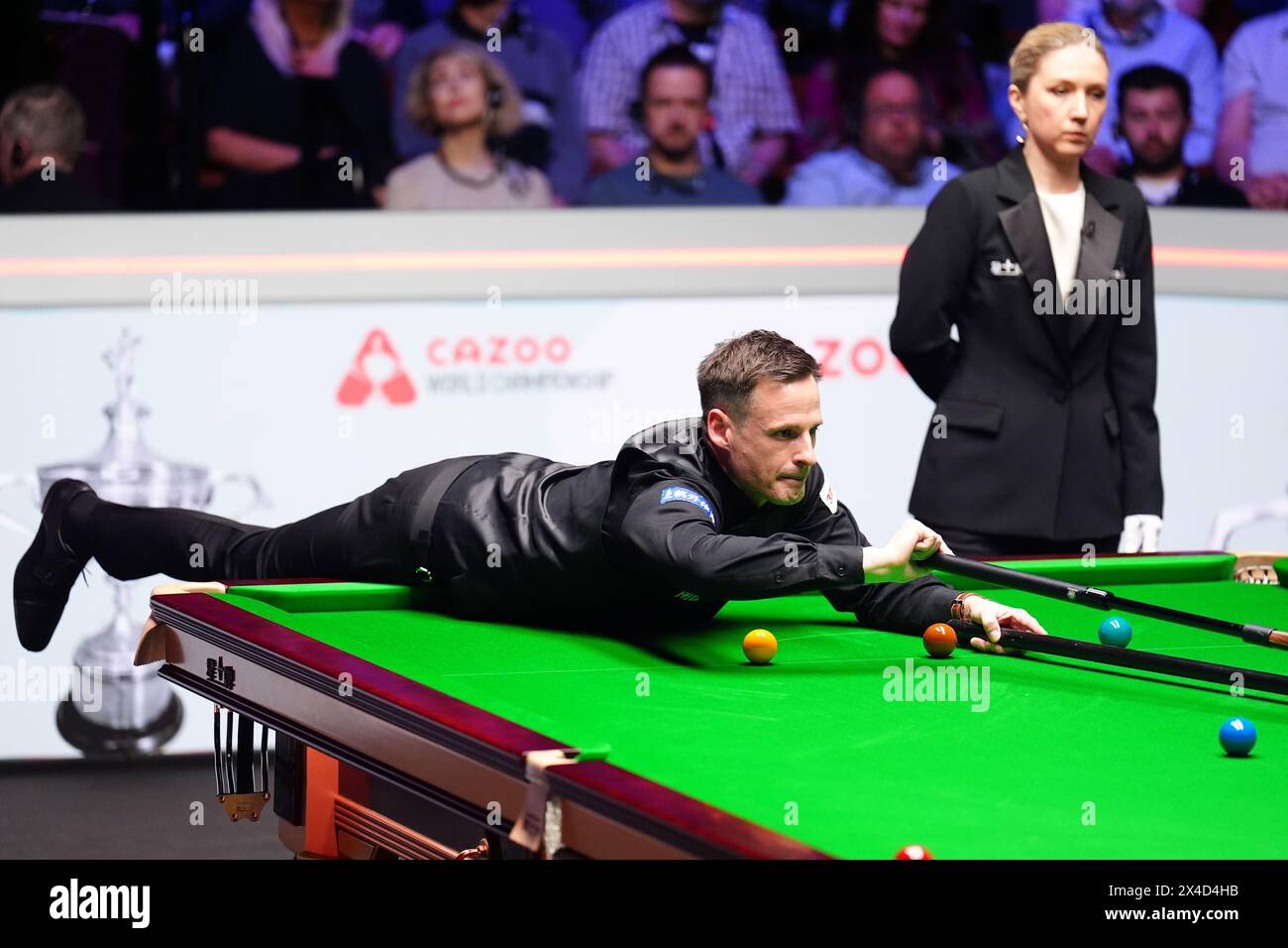 David Gilbert in action against Kyren Wilson (not pictured) as referee Tatiana Woollaston (right) looks on during the semi-final match on day thirteen of the 2024 Cazoo World Snooker Championship at the Crucible Theatre, Sheffield. Picture date: Thursday May 2, 2024. Stock Photo