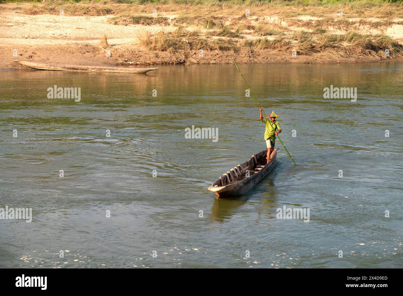 Nepal. Chitwan National Park, Sauraha, Nepali man navigating across Rapti River in canoe (Editorial Use Only) Stock Photo
