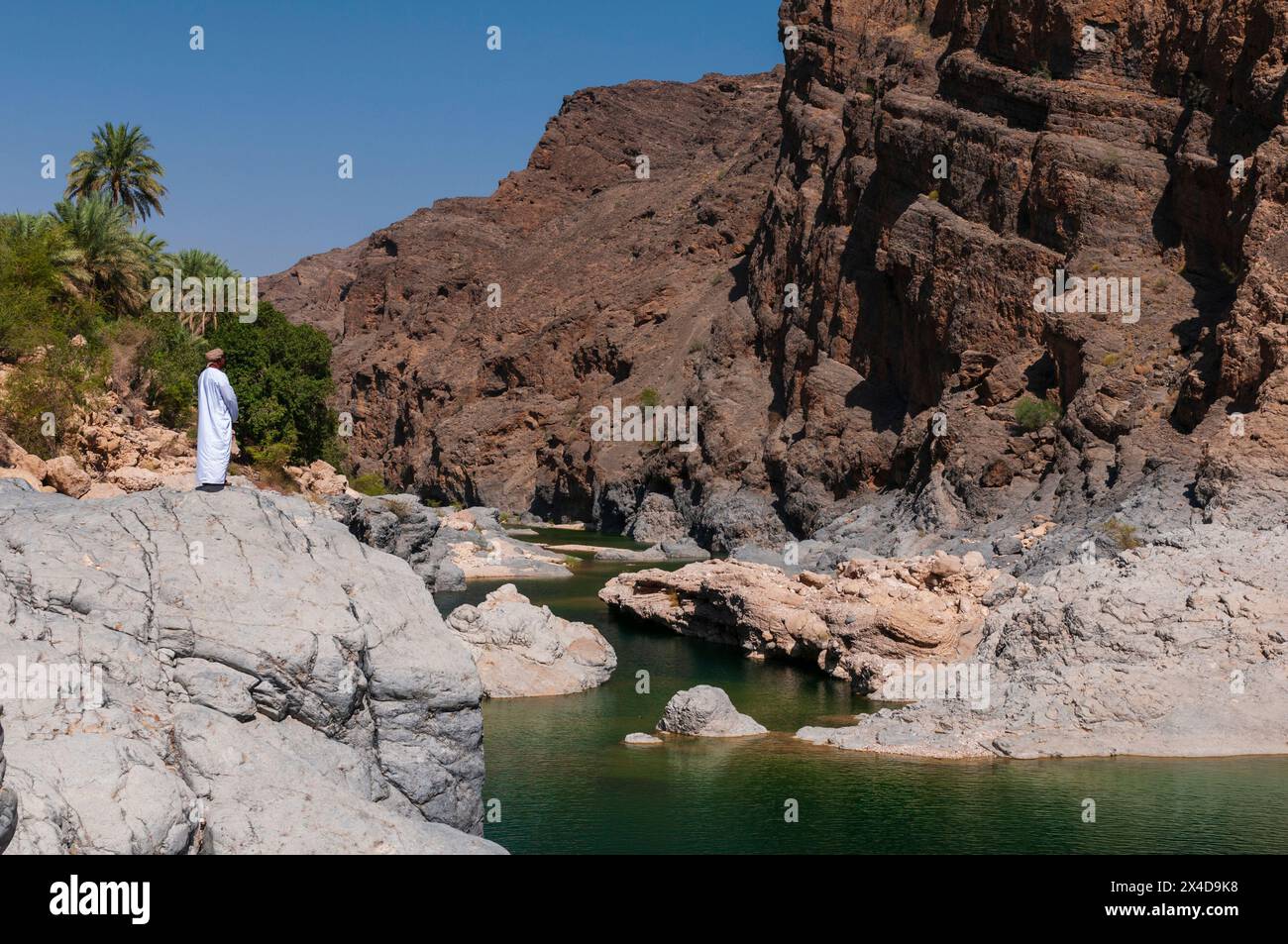 A man looking out over a natural pool in Wadi Al Arbeieen, Oman. Stock Photo