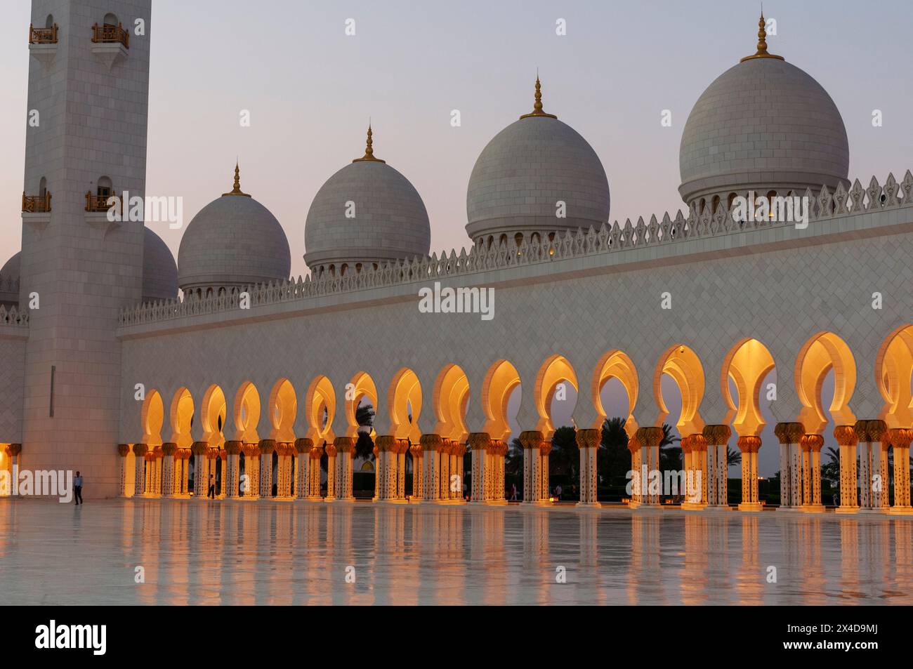 Domes and lighted archways at the Sheikh Zayed Grand Mosque at dusk. Abu Dhabi, United Arab Emirates. Stock Photo