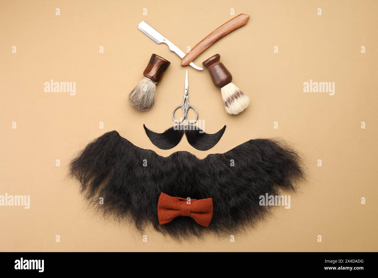 Artificial moustache, beard and barber tools on beige background, flat lay Stock Photo