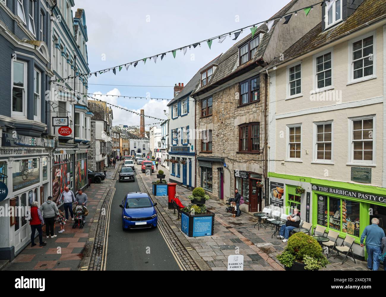 Flower tubs and bunting bring a celebratory feel to Southside Street on Plymouth’s historic Barbican. A quirky mix of small shops, public houses and r Stock Photo