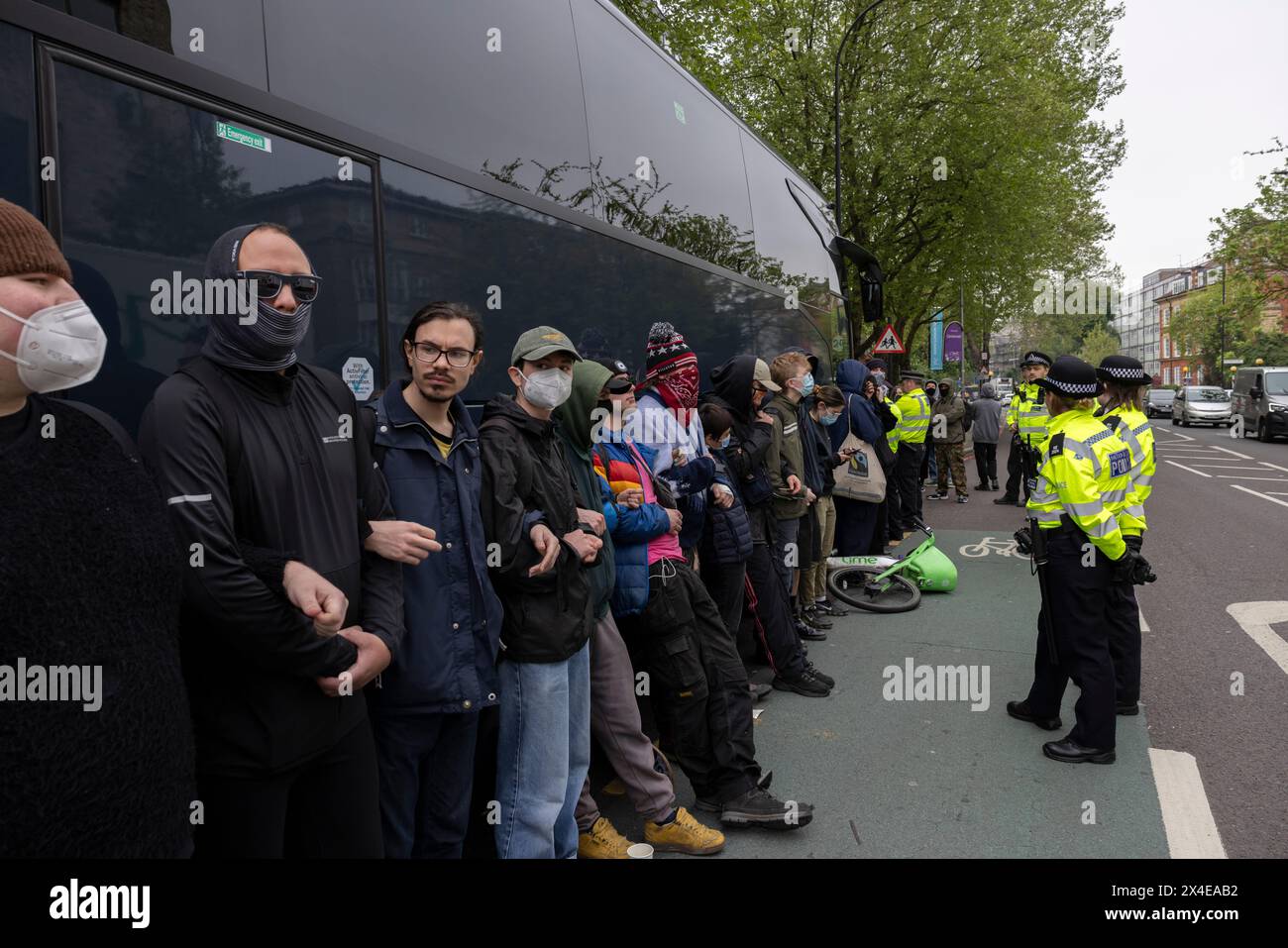 A coach sent to collect asylum seekers and take them to the Bibby Stockholm barge surrounded by protesters in Peckham south London England, UK Stock Photo