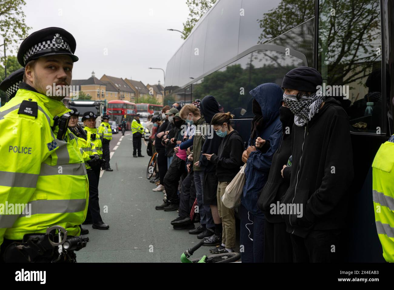 A coach sent to collect asylum seekers and take them to the Bibby Stockholm barge surrounded by protesters in Peckham south London England, UK Stock Photo