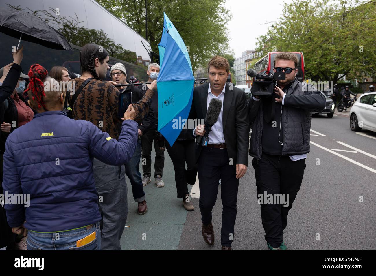 A coach sent to collect asylum seekers and take them to the Bibby Stockholm barge surrounded by protesters in Peckham south London England, UK Stock Photo