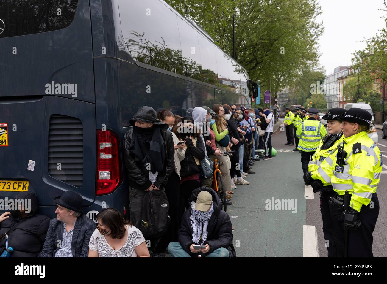 A coach sent to collect asylum seekers and take them to the Bibby Stockholm barge surrounded by protesters in Peckham south London England, UK Stock Photo