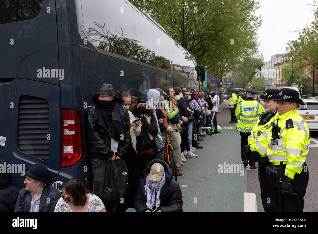 A coach sent to collect asylum seekers and take them to the Bibby Stockholm barge surrounded by protesters in Peckham south London England, UK Stock Photo