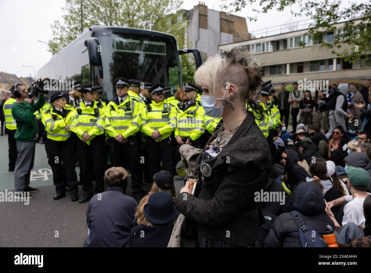 A coach sent to collect asylum seekers and take them to the Bibby Stockholm barge surrounded by protesters in Peckham south London England, UK Stock Photo