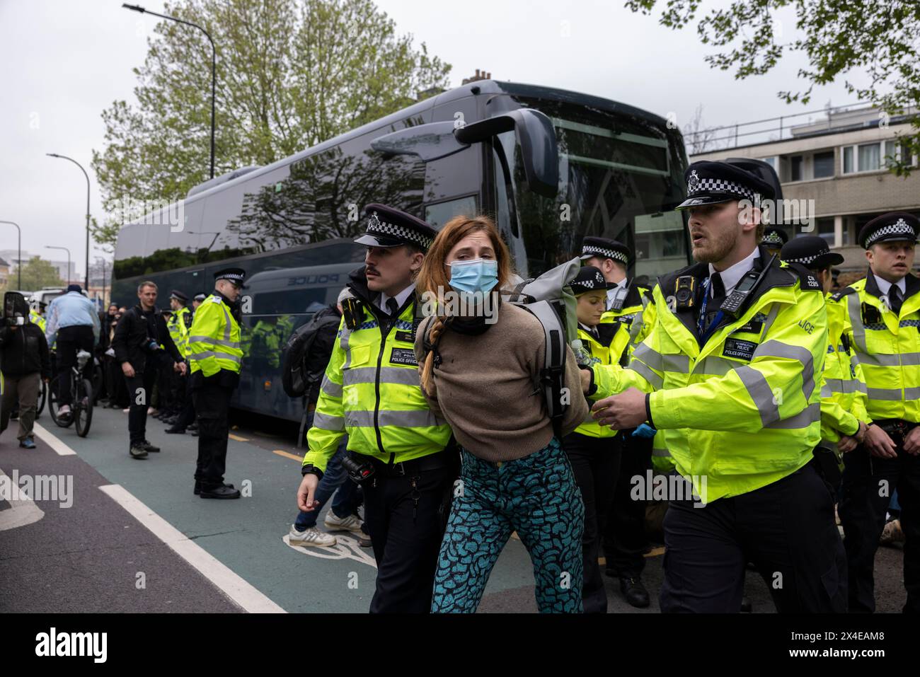 A coach sent to collect asylum seekers and take them to the Bibby Stockholm barge surrounded by protesters in Peckham south London England, UK Stock Photo