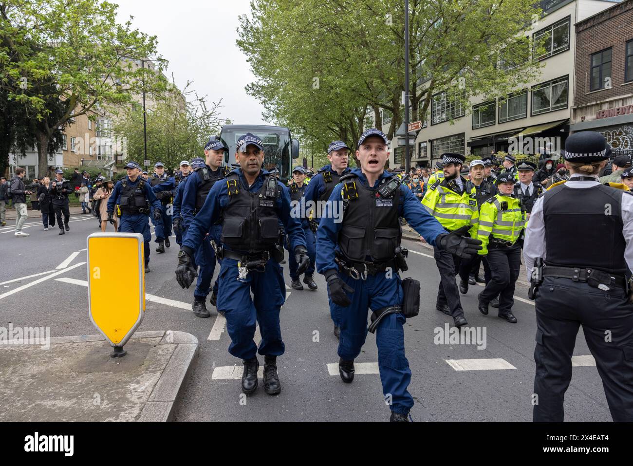 A coach sent to collect asylum seekers and take them to the Bibby Stockholm barge surrounded by protesters in Peckham south London England, UK Stock Photo