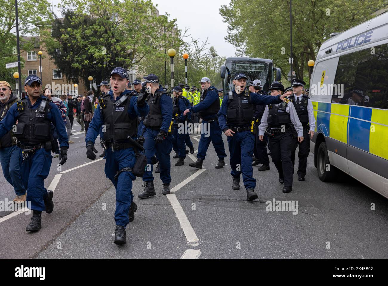 A coach sent to collect asylum seekers and take them to the Bibby Stockholm barge surrounded by protesters in Peckham south London England, UK Stock Photo