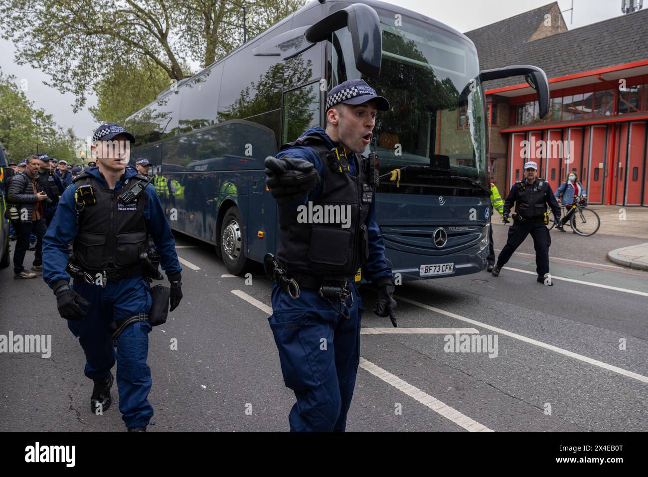 A coach sent to collect asylum seekers and take them to the Bibby Stockholm barge surrounded by protesters in Peckham south London England, UK Stock Photo