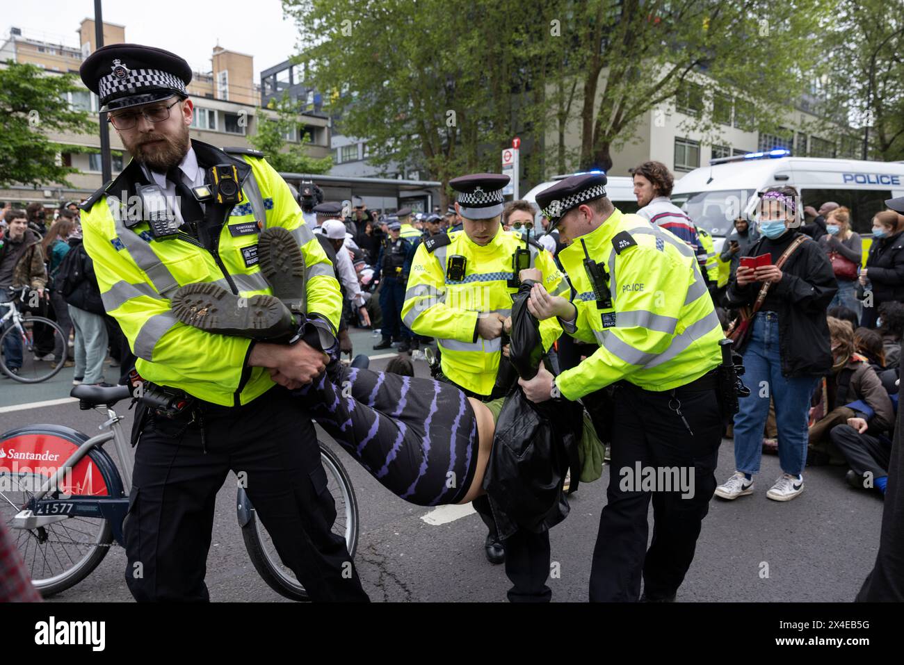 A coach sent to collect asylum seekers and take them to the Bibby Stockholm barge surrounded by protesters in Peckham south London England, UK Stock Photo